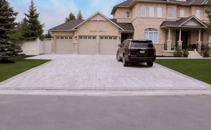 Driveway design featuring Trevista Pavers in 80mm thickness with a Grey mix color and smooth surface laid in a random pattern. Adelaide Pavers in Ultra Black are used as the soldier course for a sleek finish.