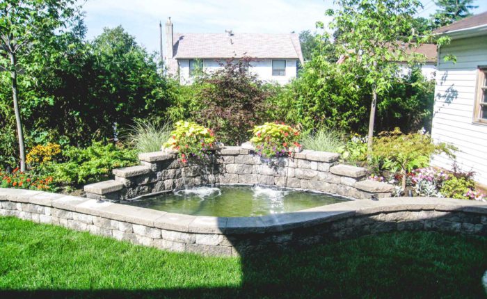 Retaining wall design featuring a waterfall feature and pond integrated into it, with planting behind the wall and waterfall.