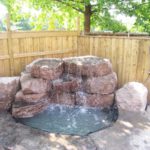 Waterfall feature surrounded by natural stone with a pond.