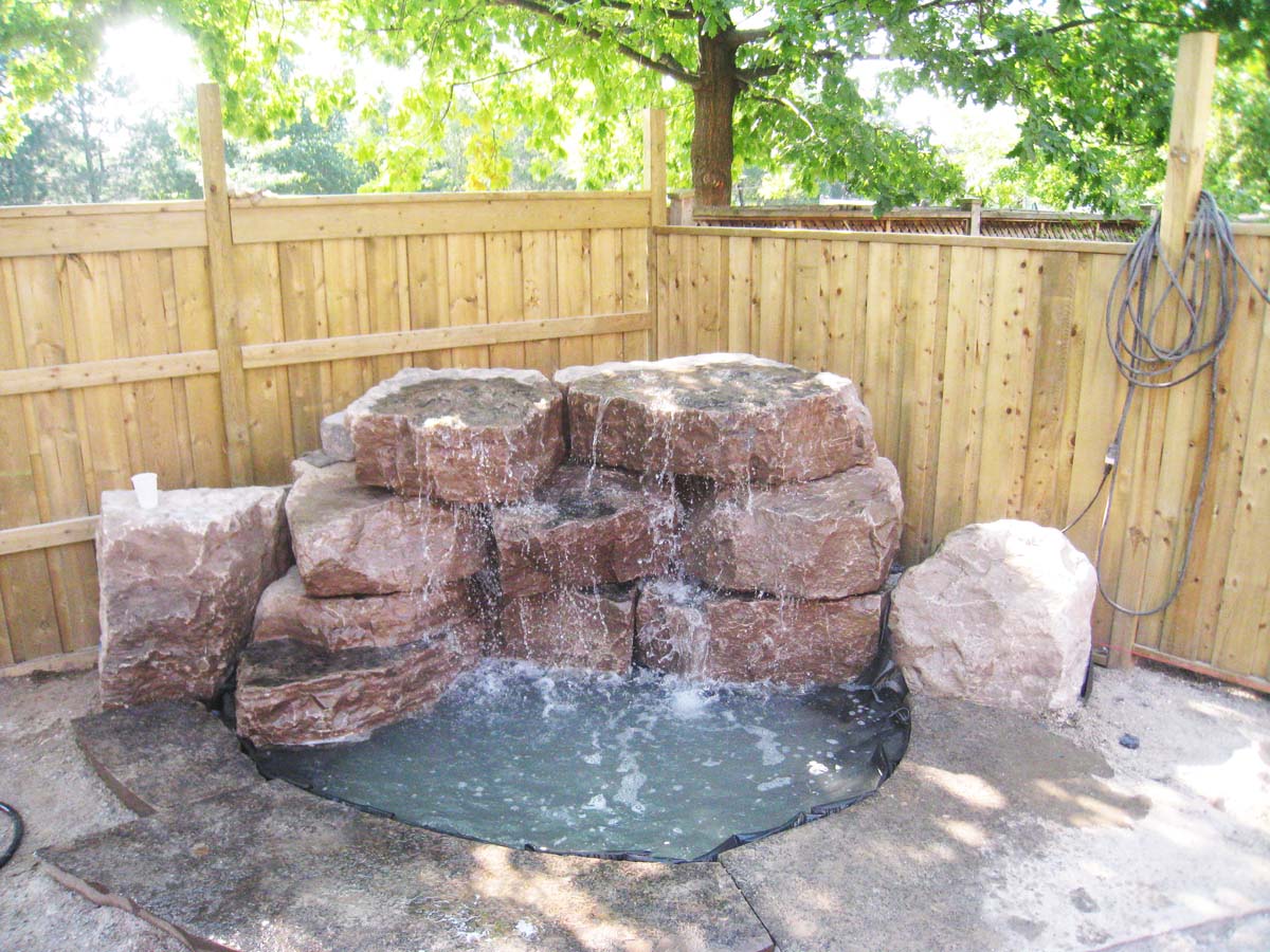 Waterfall feature surrounded by natural stone with a pond.