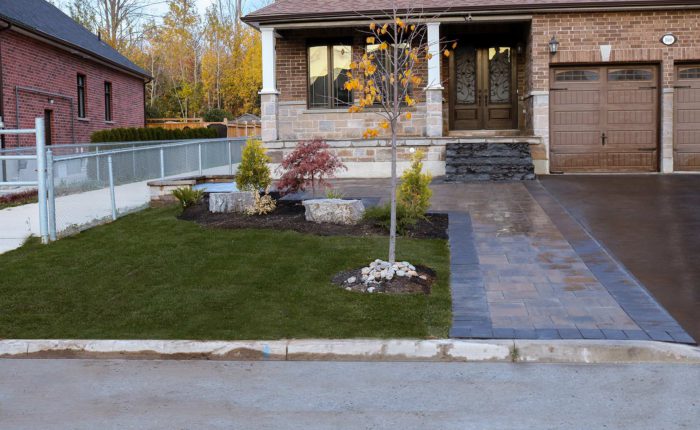 Driveway design featuring textured Trevista Pavers in 80mm thickness with a Beige mix color. Additionally, there are Richmond Pavers in Ultra Black used as the soldier course. The driveway is accented with three natural stone Ultra Black steps leading to the front entrance.