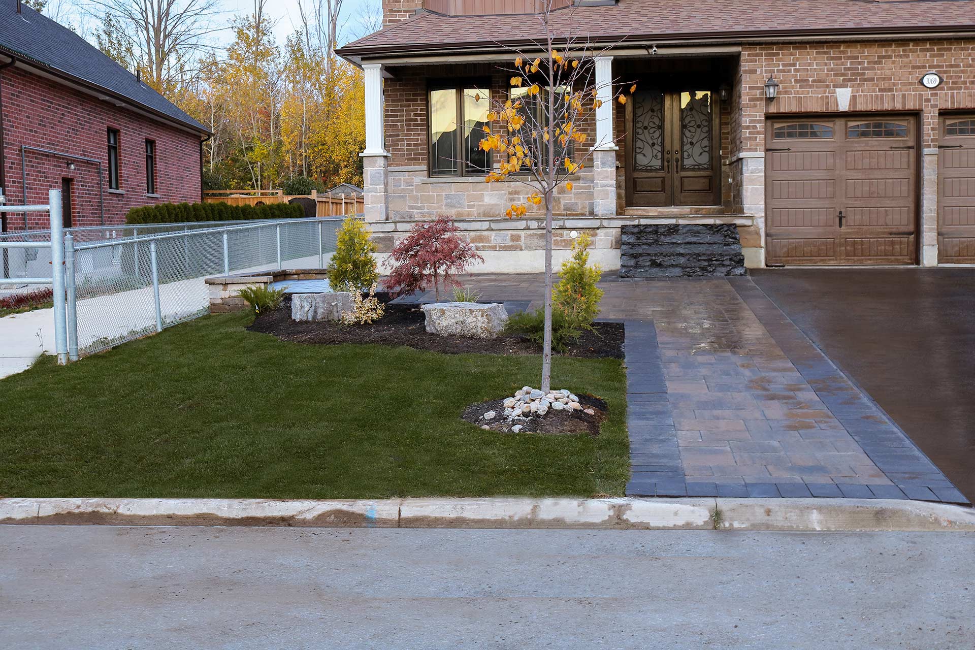 Driveway design featuring textured Trevista Pavers in 80mm thickness with a Beige mix color. Additionally, there are Richmond Pavers in Ultra Black used as the soldier course. The driveway is accented with three natural stone Ultra Black steps leading to the front entrance.